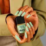 Hand holding Soft Meadow Green Nail Polish with Smooth Matte Finish bottle with painted nails